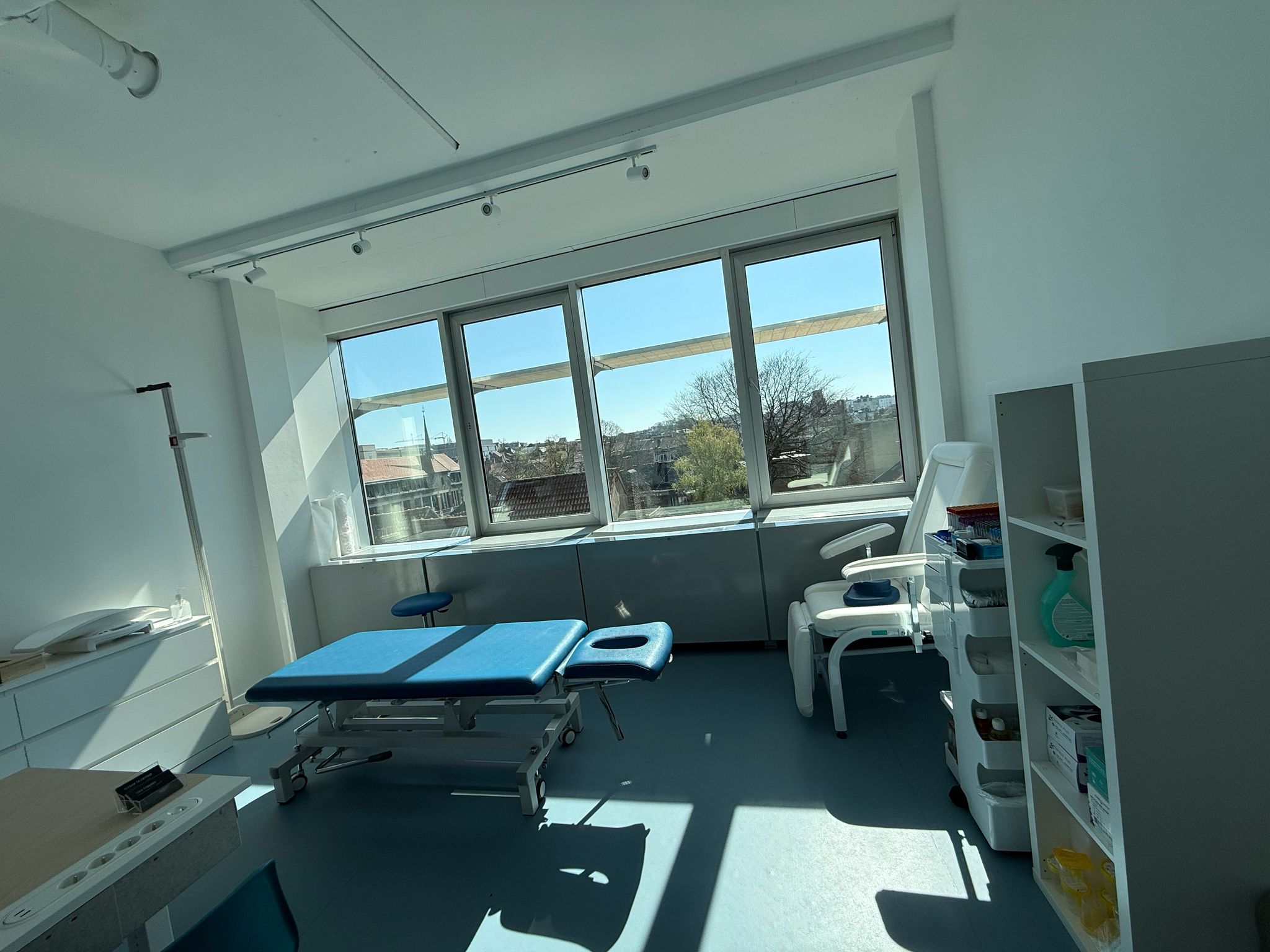Cabinet B2M Sport & Rehab, espace lumineux entièrement blanc avec une table de consultation bleue.